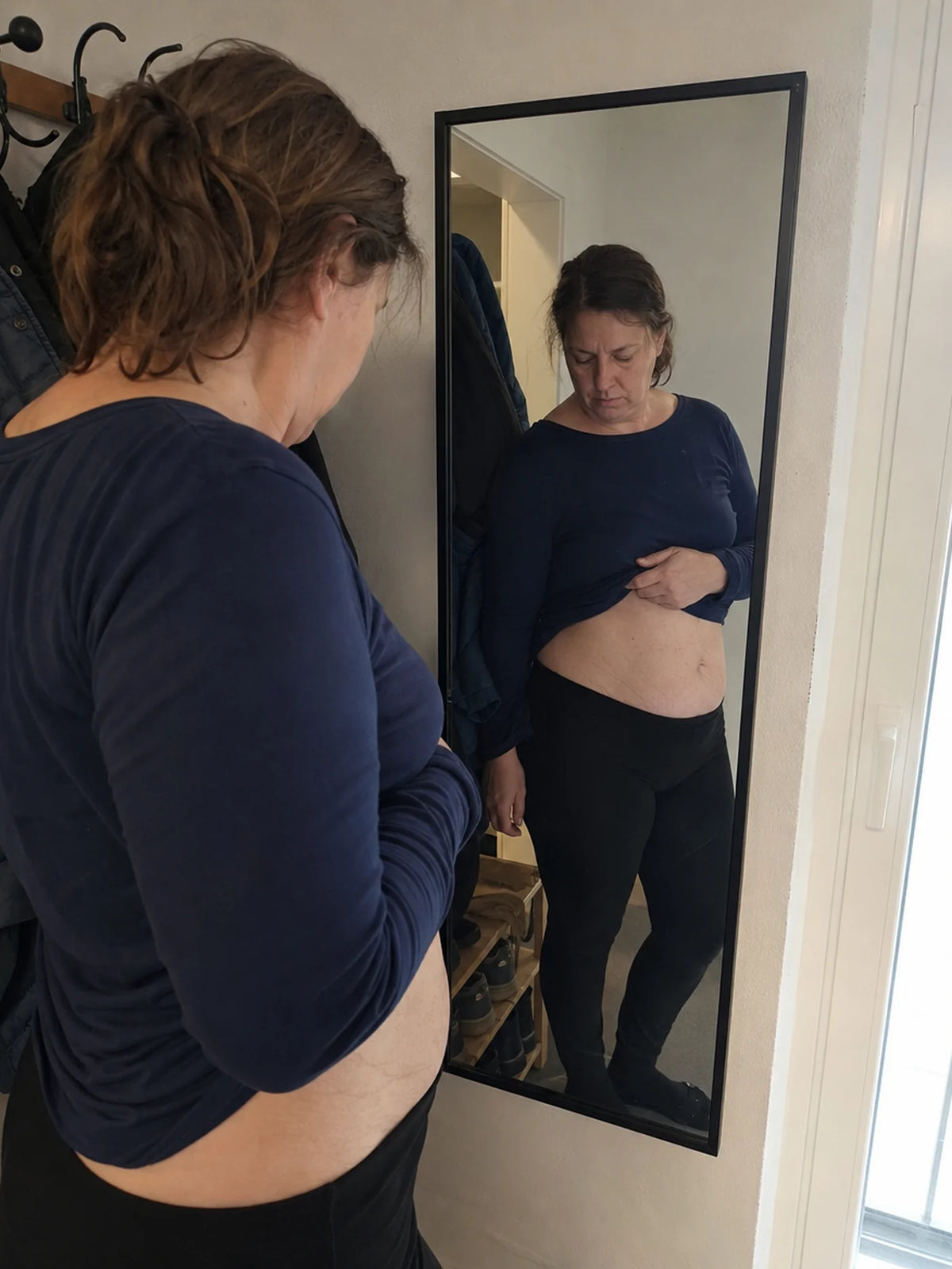 Femme devant son miroir, ventre après la grossesse