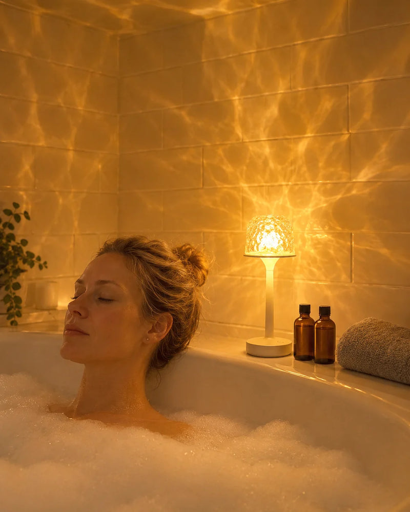 Femme qui se détend dans son bain, lampe Aurora et reflets dorés sur les murs